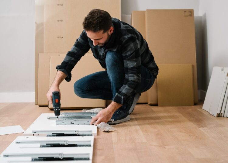 Portrait of man assembling furniture. Do it yourself furniture assembly.